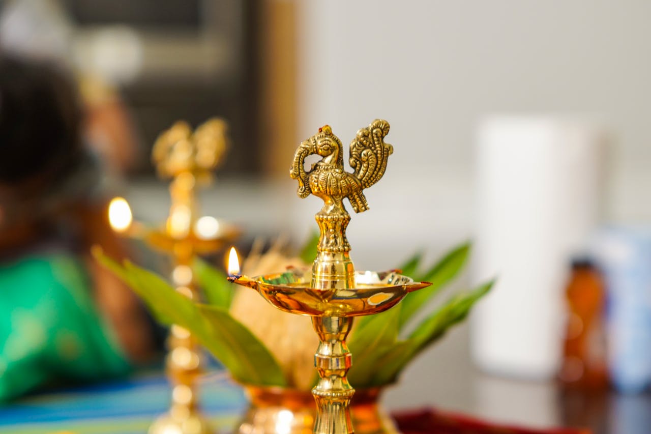 Close-up of a traditional Indian brass oil lamp with intricate design, beautifully lit indoors.